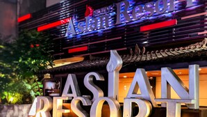 Cartel para Asian Resort con letras iluminadas y un diseño arquitectónico tradicional.