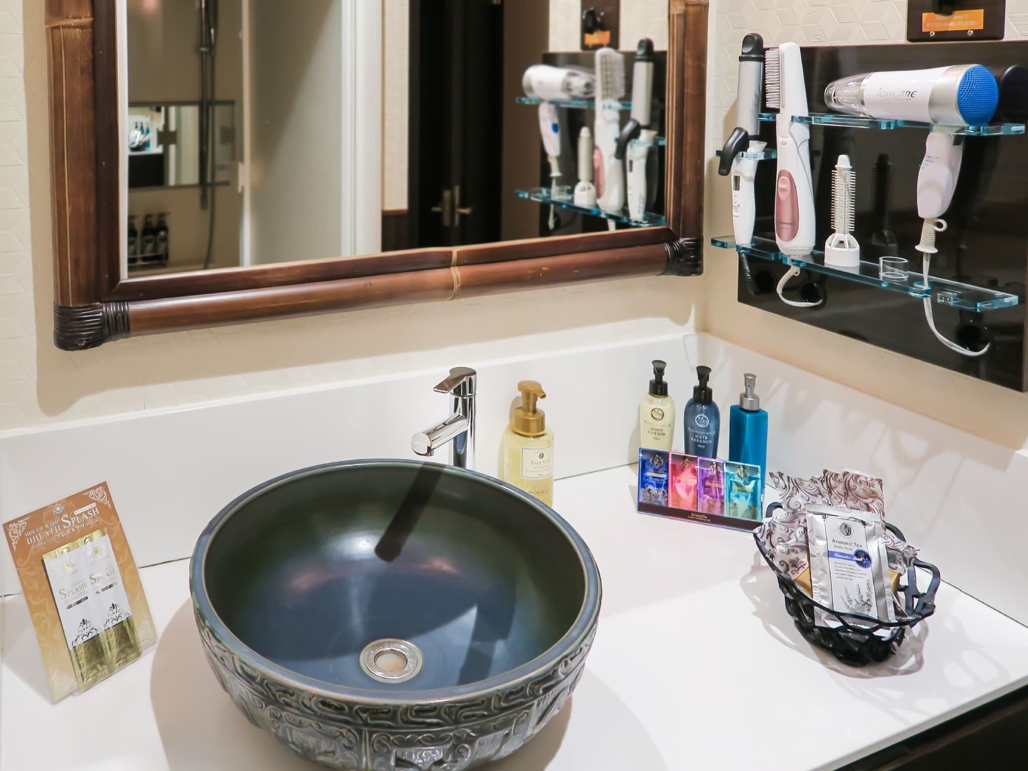 A bathroom with a large mirror, a sink with a decorative bowl, and various toiletries on the counter.