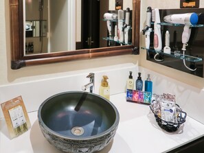 A bathroom with a large mirror, a sink with a decorative bowl, and various toiletries on the counter. - Hotel Asian Resort (Sendai)