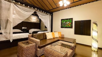 Una habitación con una cama bajo dosel, un sofá con cojines, una mesa de centro tejida y una obra de arte colgada en la pared.
