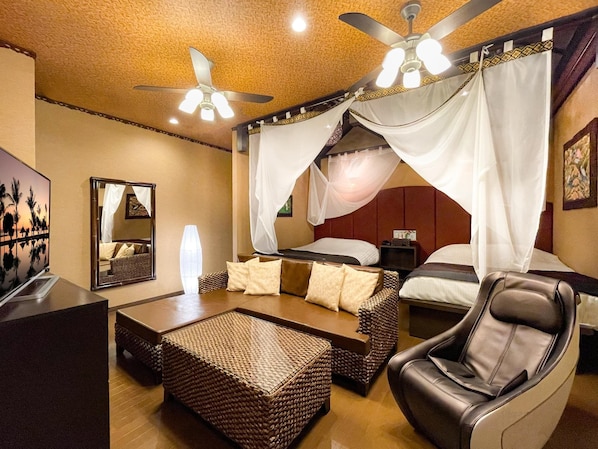 A hotel room with a bed, a chair, a sofa, a TV, and a ceiling fan. - Hotel Asian Resort (Sendai)