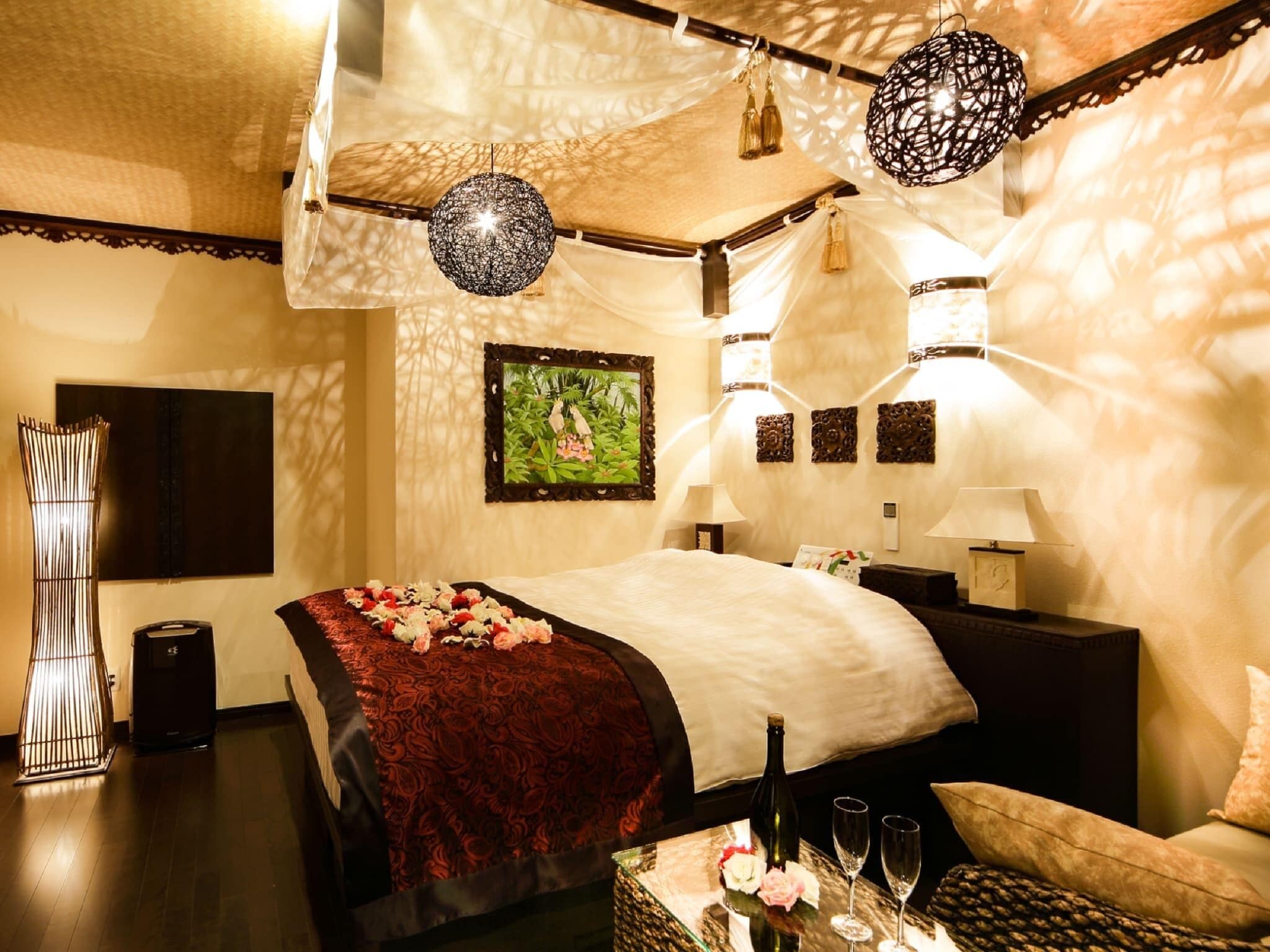 A hotel room with a bed, bedside tables, a nightstand, a lamp, a chair, and a decorative wall piece.