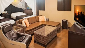 Una habitación de hotel con cama, sofá, televisor y altavoz.