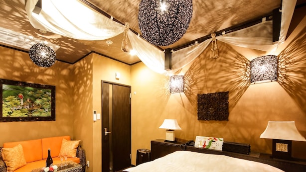 Una habitación de hotel con cama, sofá, mesita de noche y lámpara de pared.