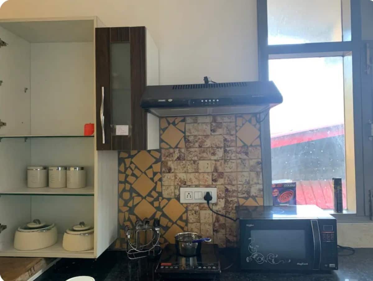 A kitchen with a microwave, a stove, and a tiled backsplash.