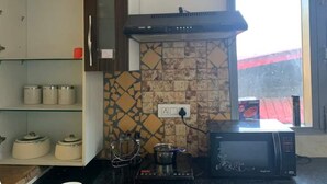A kitchen with a microwave, a stove, and a tiled backsplash. - Rustic Pines (Solan)