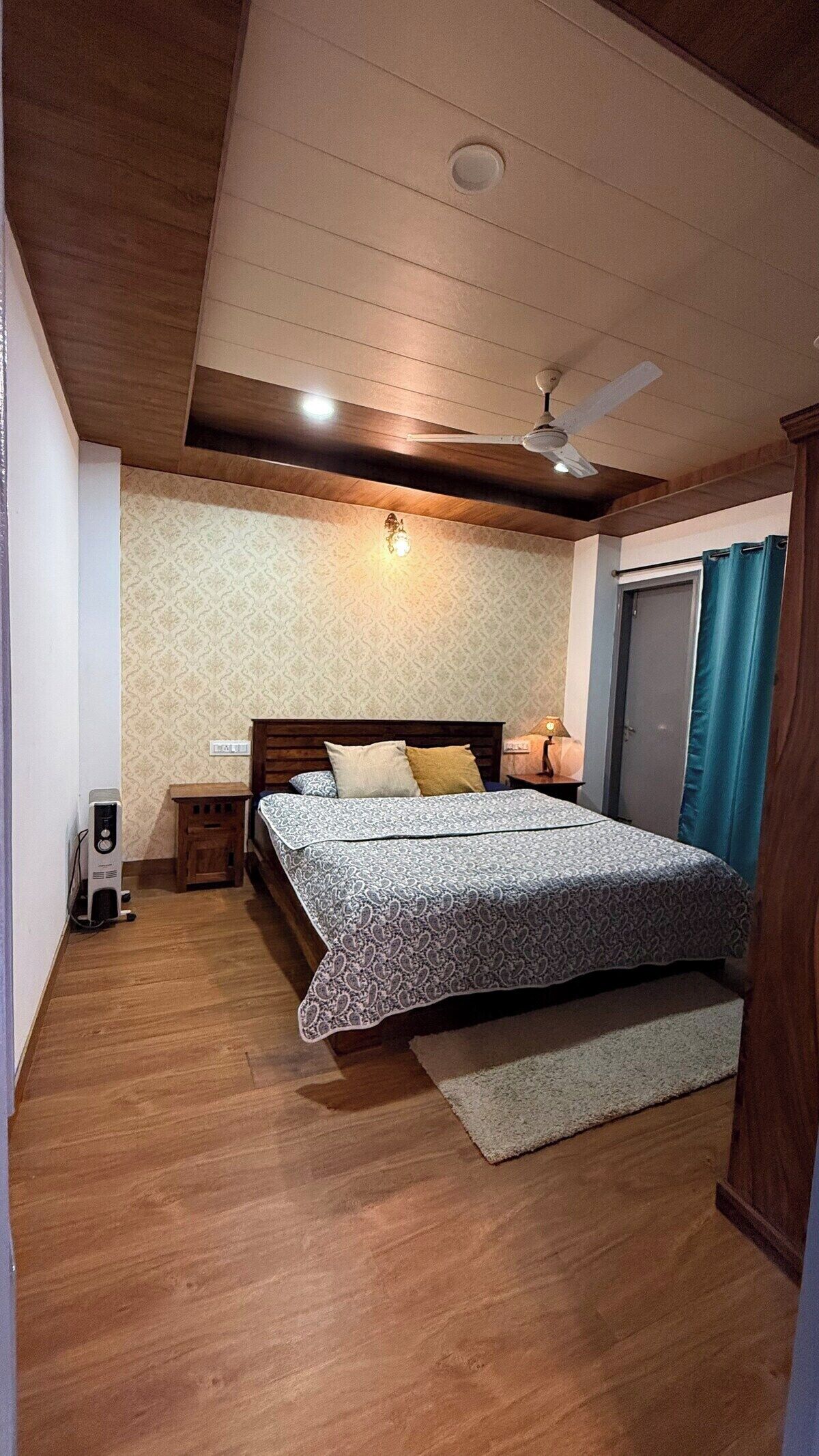 A bedroom with a bed, a nightstand, a ceiling fan, and a wall-mounted light.