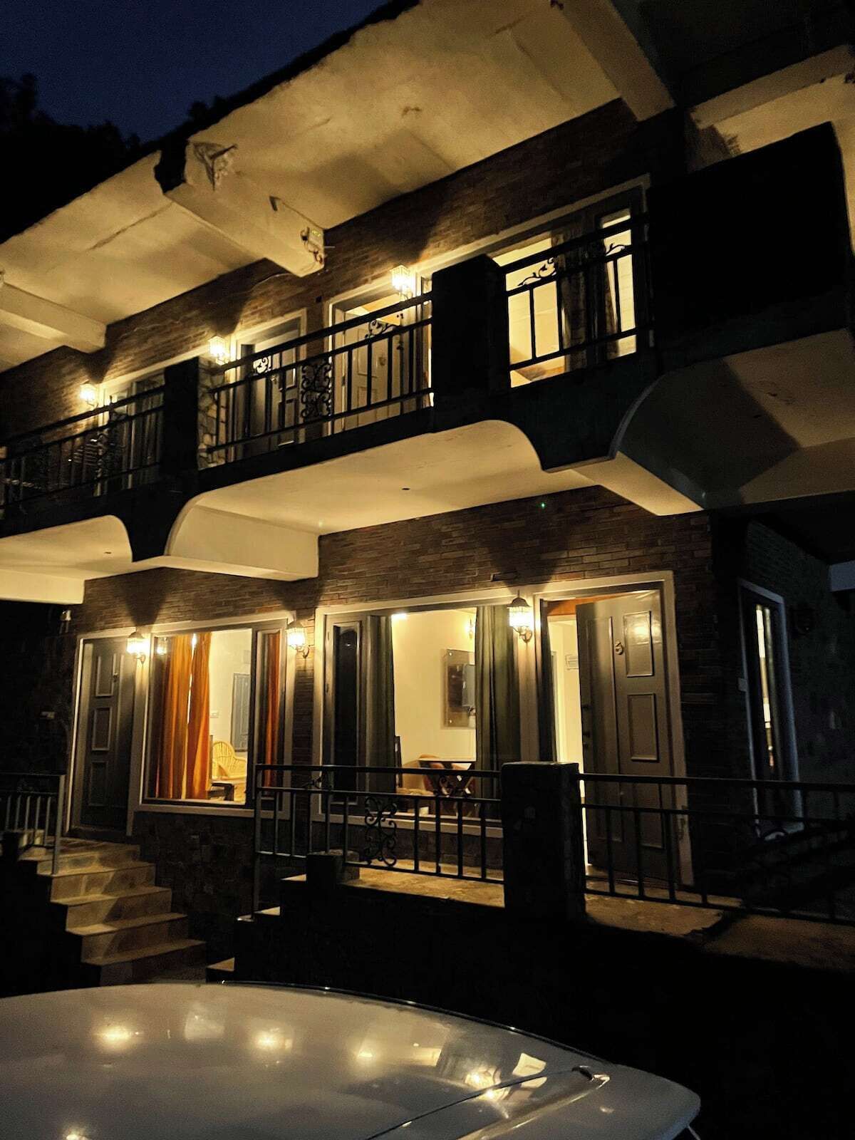 A two-story building with a balcony, a hot tub, and a staircase leading to the entrance.