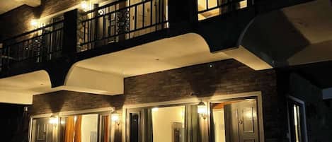 A two-story building with a balcony, a hot tub, and a staircase leading to the entrance.
