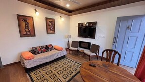 A living room with a sofa, chairs, a TV, and a dining table. - Rustic Pines (Solan)