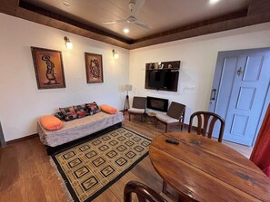 A living room with a sofa, chairs, a TV, and a dining table. - Rustic Pines (Solan)