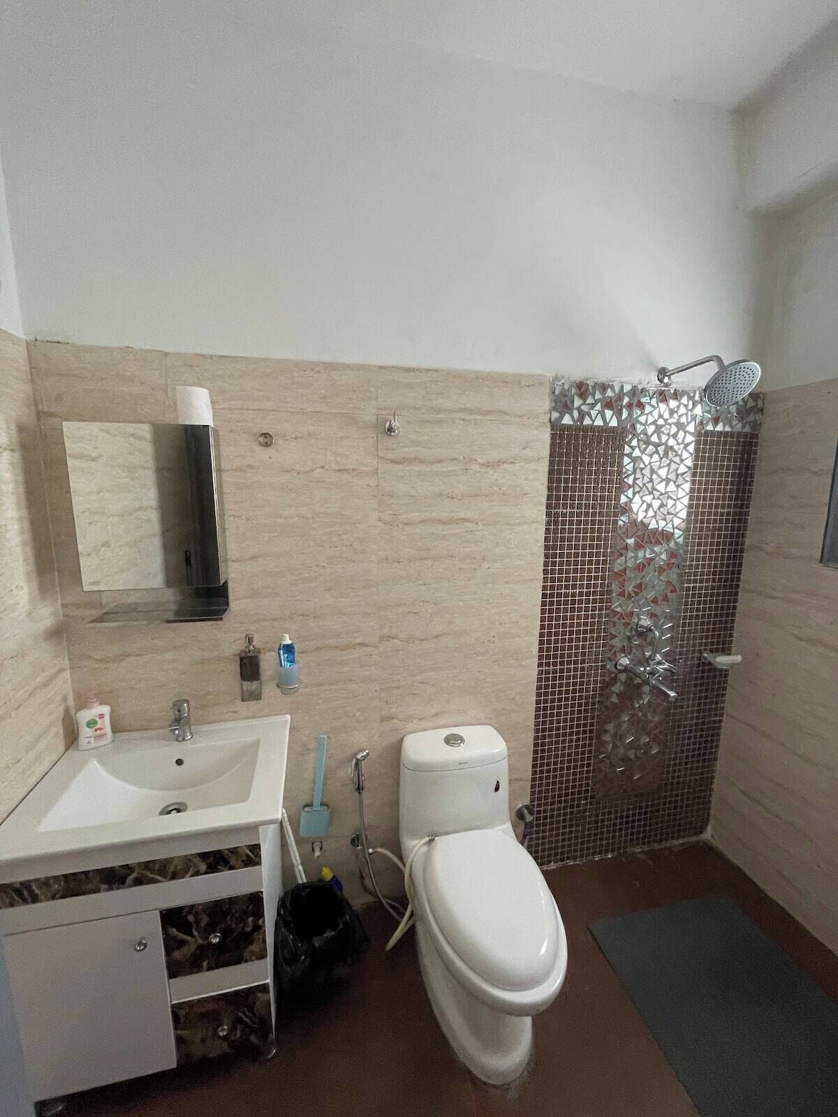 Et badeværelse med vask, spejl, toilet og brusebad.