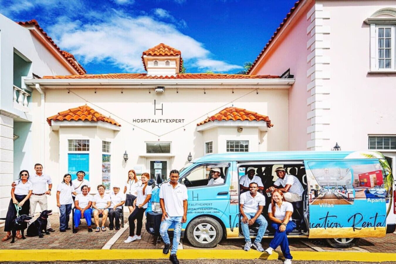 A group of people standing in front of a building with a sign that reads "HOSPITALITY EXPERT."