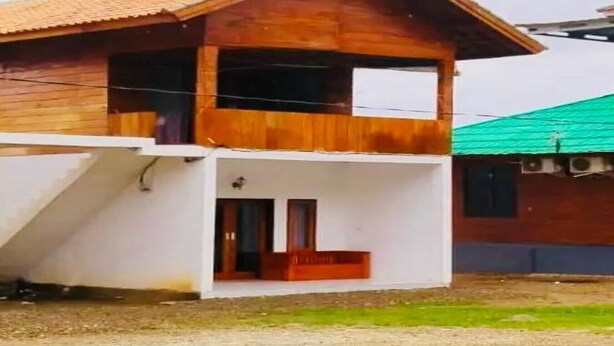 A two-story wooden house with a balcony, a white lower level, and a green roof. - Cozzy Villa Dua Bidadari (Jawa Barat)