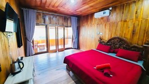 A wooden-paneled room with a bed, a desk, and a television. - Cozzy Villa Dua Bidadari (Jawa Barat)