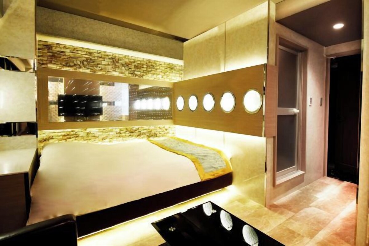 A modern hotel room with a large bed, a built-in desk, and a unique wall design with circular lights.
