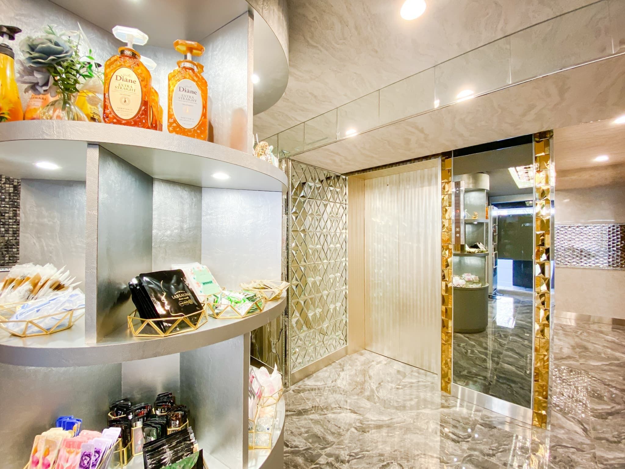 A modern hotel lobby with marble flooring, a reception desk, and a decorative wall.