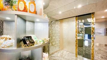 A modern hotel lobby with marble flooring, a reception desk, and a decorative wall.