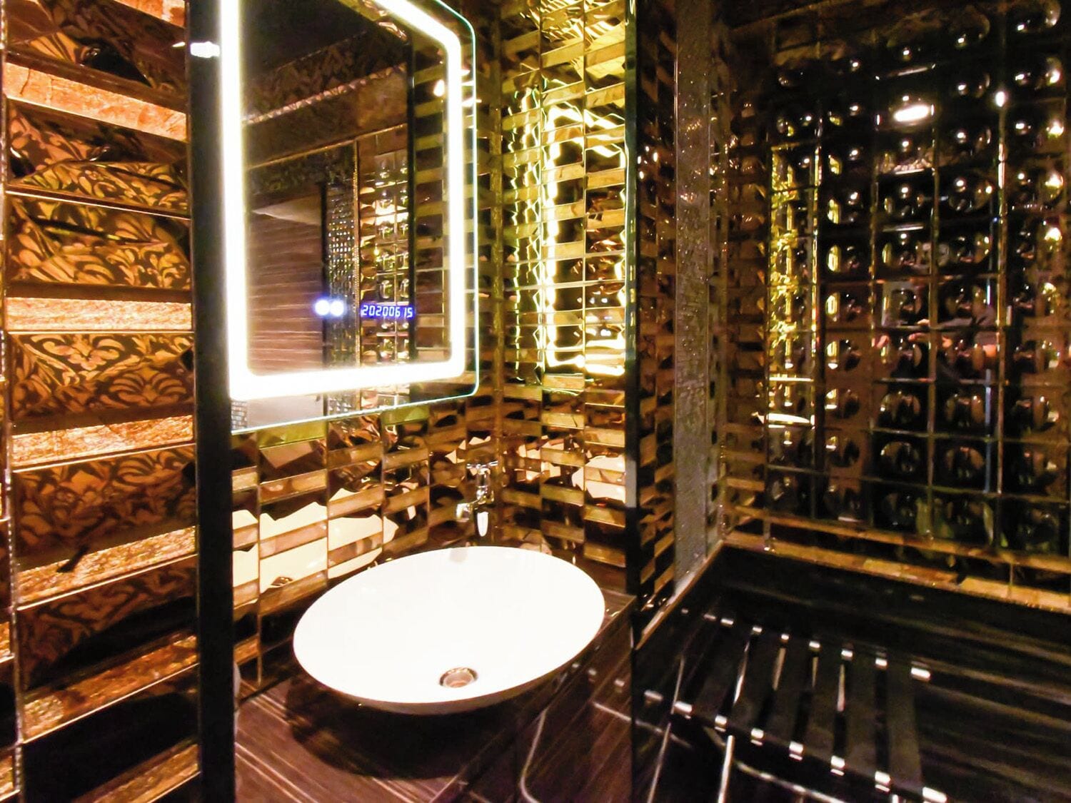 A bathroom with a round sink, a mirror with a light, and a patterned wall.