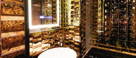 Un baño con un lavamanos redondo, un espejo con luz y una pared con diseño.