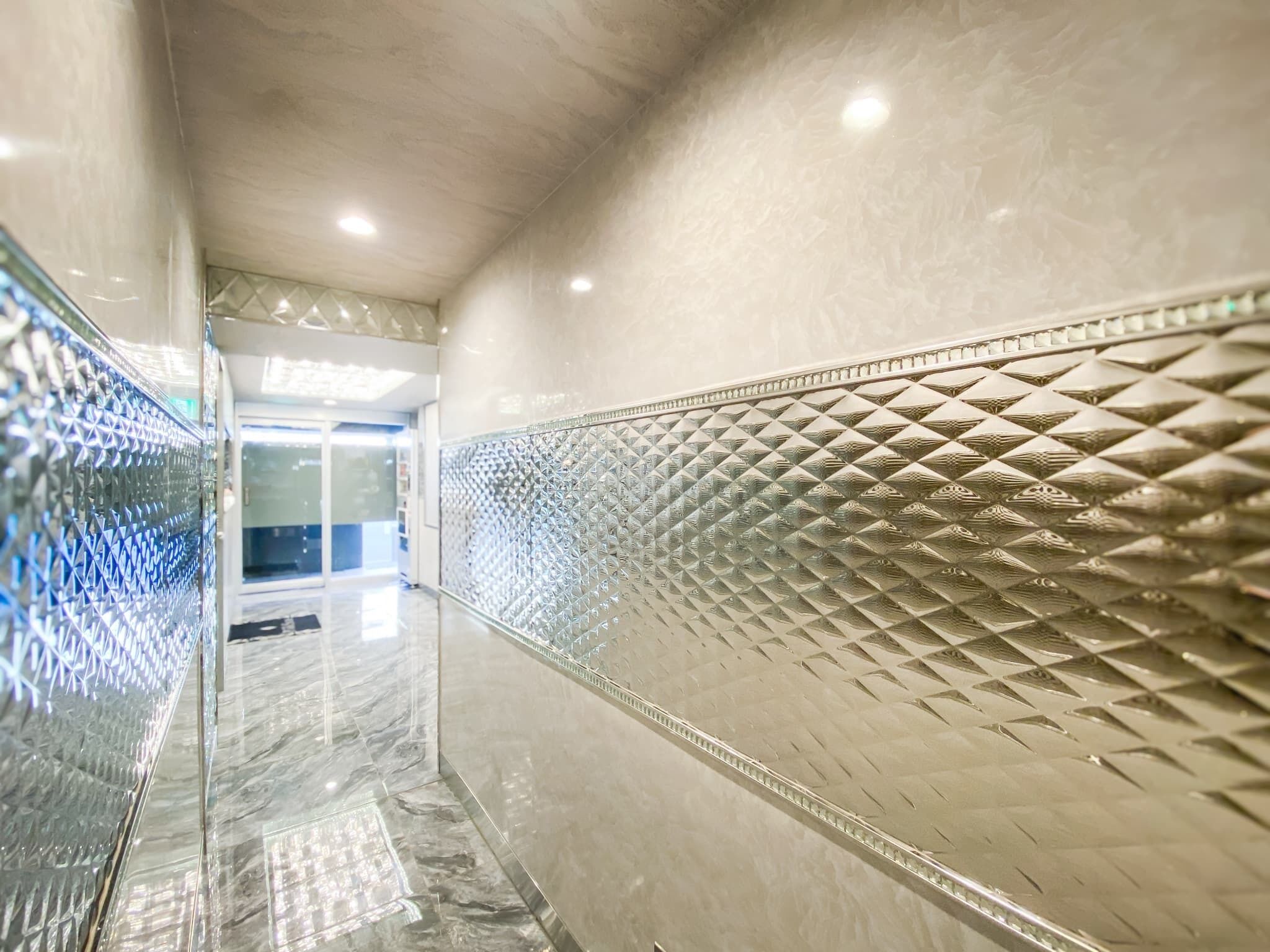 Un pasillo con paneles de vidrio reflectante y paneles de pared texturizados.