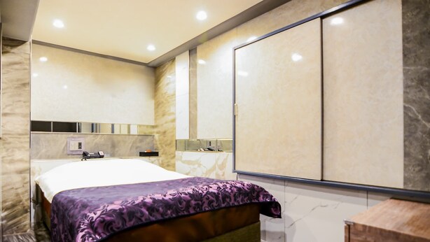 Una habitación de hotel moderna con una cama grande, armario empotrado y baño con espejo y lavabo.