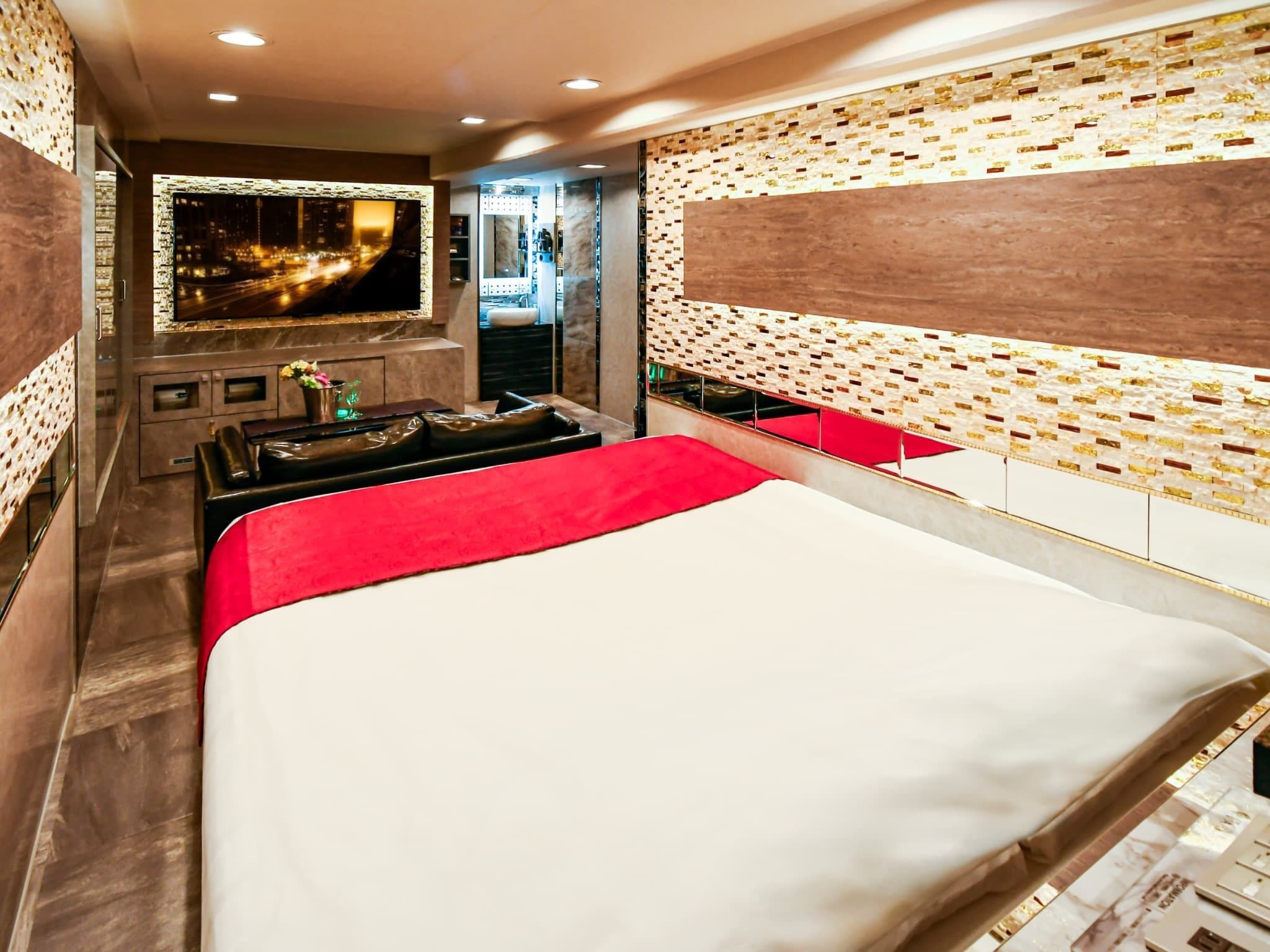 A modern hotel room with a large bed, a TV, and a minibar.