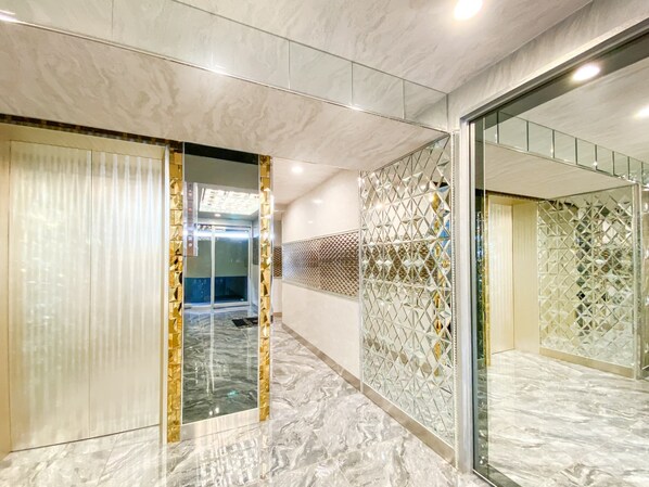 A modern interior with a marble floor, a glass partition, and a geometric patterned wall.