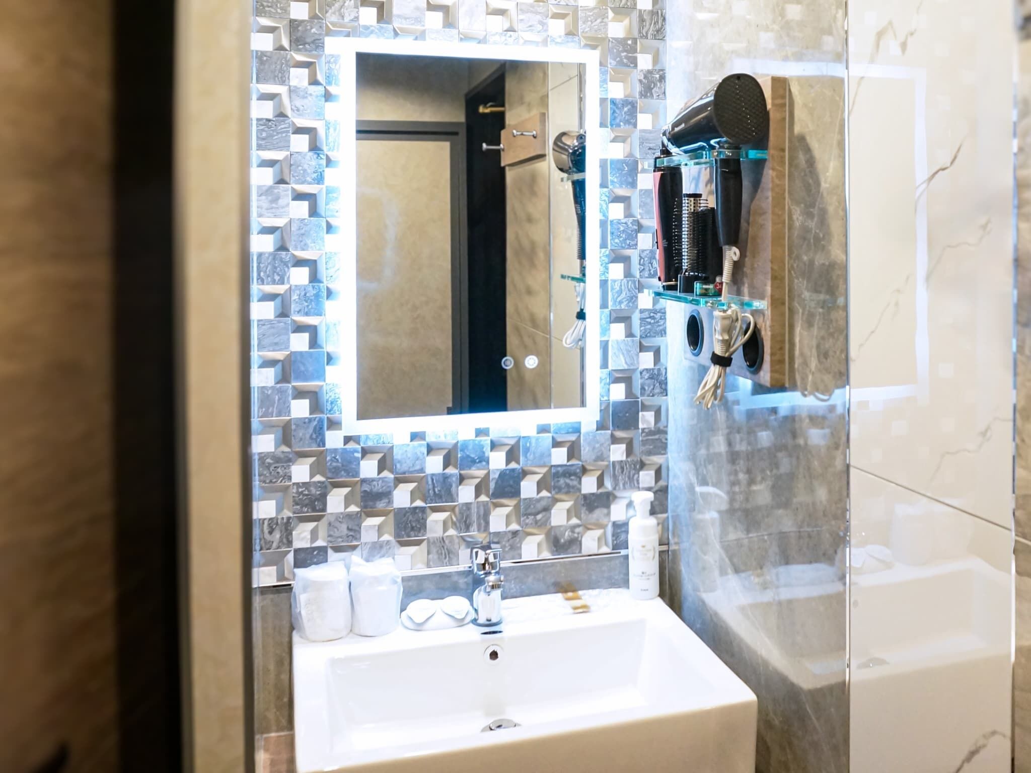 Un baño con lavamanos, espejo y dispensador de toallas.