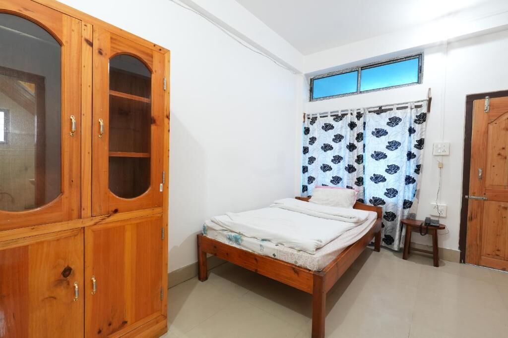 A bedroom with a wooden bed, a wardrobe, a window with curtains, and a door.