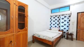 A bedroom with a wooden bed, a wardrobe, a window with curtains, and a door.