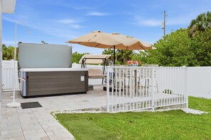 A patio area with a white fence, a beige umbrella, and outdoor furniture. -   Spacious 3-BD Home with Private Hot Tub Near the Beautiful Boca Grande Beaches (Placida)