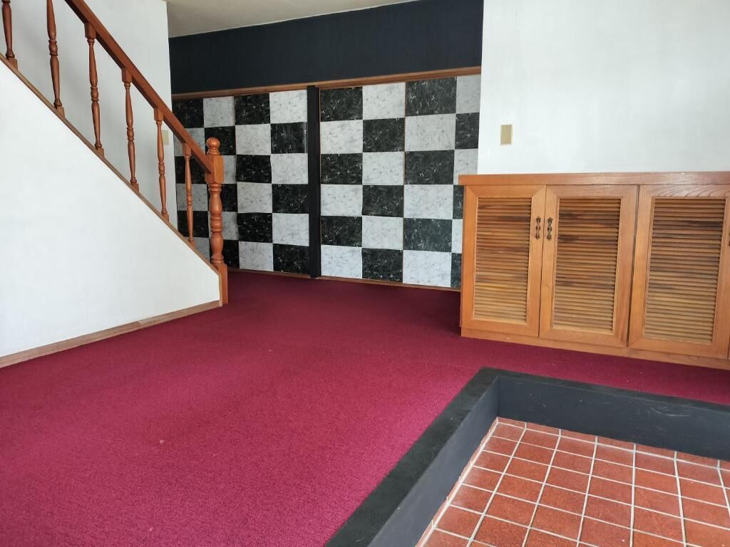 A staircase with wooden balusters, a checkered wall, and a red carpeted floor.