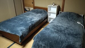A room with two beds, a white shelf unit, and a wooden wardrobe. - Guesthouse Naruto Ohenro (Naruto)