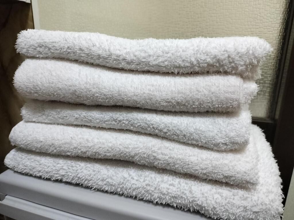 A stack of white towels on a white surface.