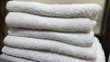 A stack of white towels on a white surface.