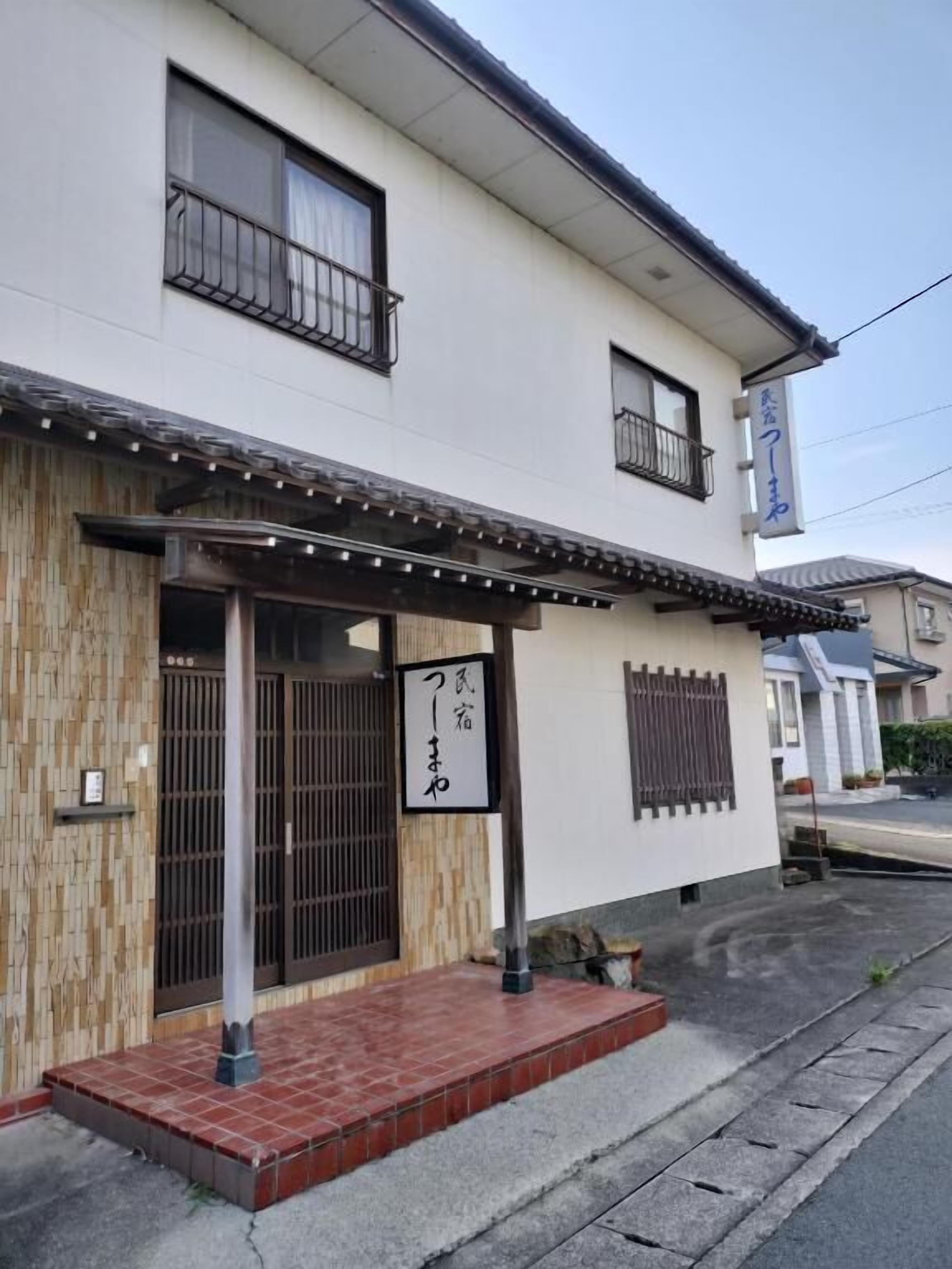 Un bâtiment traditionnel japonais, doté d’une entrée en bois, d’un porche carrelé et d’une enseigne avec des caractères japonais.
