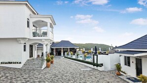Un patio de hotel con suelo de baldosas estampadas, zona de piscina y área de estar cubierta.