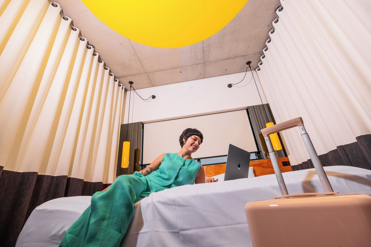 Una habitación de hotel con una cama, una maleta y un ordenador portátil.