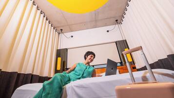 A hotel room with a bed, a suitcase, and a laptop.
