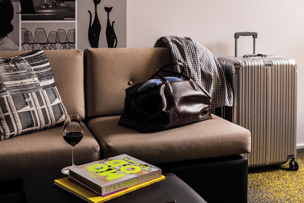 Un canapé, un livre, un verre de vin, un sac à main et une valise.