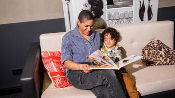 A person sitting on a couch with a child, reading a book.