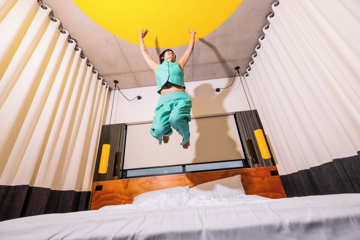 Una habitación con cama, cortinas y lámpara en el techo.