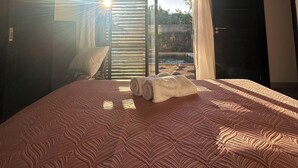 A bedroom with a bed, a ceiling fan, a view through a window, and a door. - Luxury Private 3BR Villa with Private Pool Near Pereybere Beach  Sleeps 6 (Grand Baie)