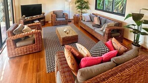 A spacious living room with wicker furniture, a ceiling fan, and large windows. - Luxury Private 3BR Villa with Private Pool Near Pereybere Beach  Sleeps 6 (Grand Baie)