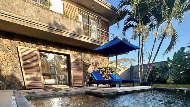 A swimming pool with clear water, surrounded by a stone border and a row of white pebbles. - Luxury Private 3BR Villa with Private Pool Near Pereybere Beach  Sleeps 6 (Grand Baie)