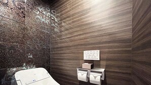 Un baño moderno con un inodoro, un dispensador de papel de pared y un motivo decorativo en la pared.