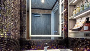 Un baño con pared de mosaicos, un lavabo blanco y un espejo.