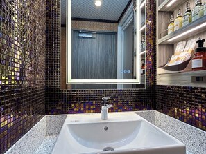 Un baño con pared de mosaicos, un lavabo blanco y un espejo.