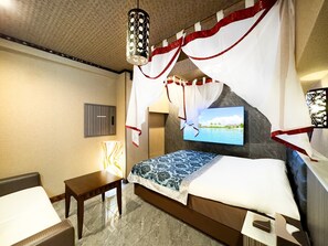 Ein Hotelzimmer mit Bett, Wandfernseher, Nachttisch und Lampe.
